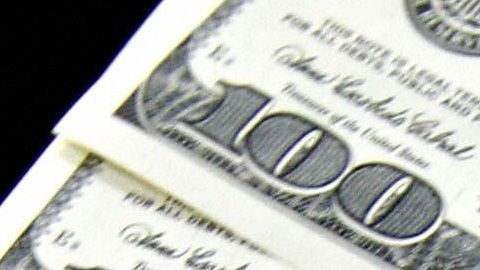 A money changer holds a wad of USD bills