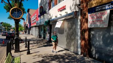 Una persona camina frente a negocios cerrados pese a reapertura, este lunes en la quinta Avenida.