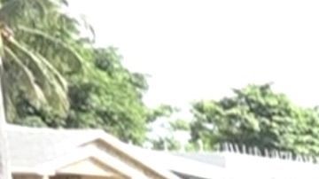 Una mujer, con máscara y guantes, esperando en fila para un entrega de mascarillas en Miami.