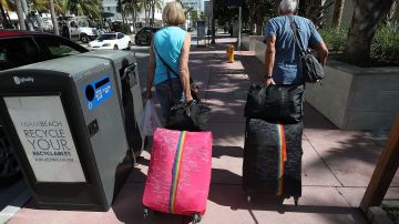 Turistas cargando maletas en Miami Beach.