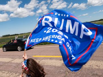 Un hombre con una bandera de apoyo a Trump.