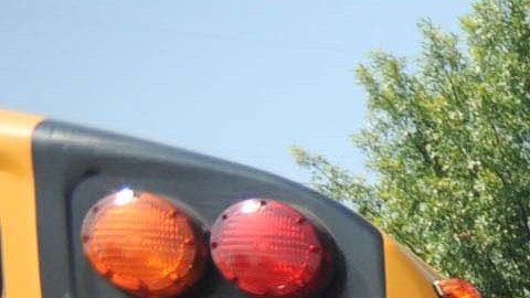 Un policía dirige el tráfico de autobuses escolares frente a una escuela pública en Illinois.