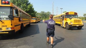 Un policía dirige el tráfico de autobuses escolares frente a una escuela pública en Illinois.