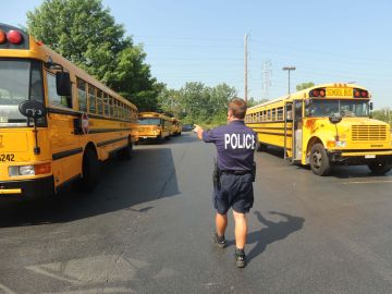 Un policía dirige el tráfico de autobuses escolares frente a una escuela pública en Illinois.