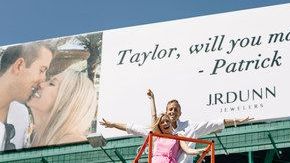 Patrick y su novia Taylor posaron frente a la valla publicitaria tras la petición de matrimonio.