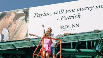 Patrick y su novia Taylor posaron frente a la valla publicitaria tras la petición de matrimonio.