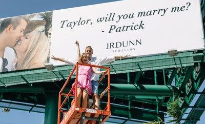 Patrick y su novia Taylor posaron frente a la valla publicitaria tras la petición de matrimonio.