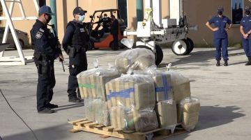 Dos oficiales custodian parte del cargamento confiscado por la Guardia Costera de Estados Unidos.