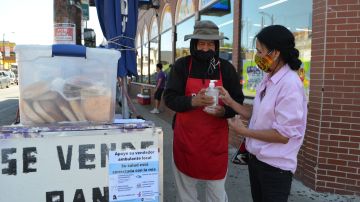 Carmen Camacho vende panes caseros al estilo mexicano en La Villita. En  su carrito fue colocado un afiche de información  para prevenir el contagio de covid-19.  (Belhú Sanabria / La Raza)