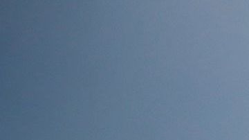 Una mujer pasando con una bicicleta frenta a un cartel de "playa cerrada" en South Beach, en Miami Beach.