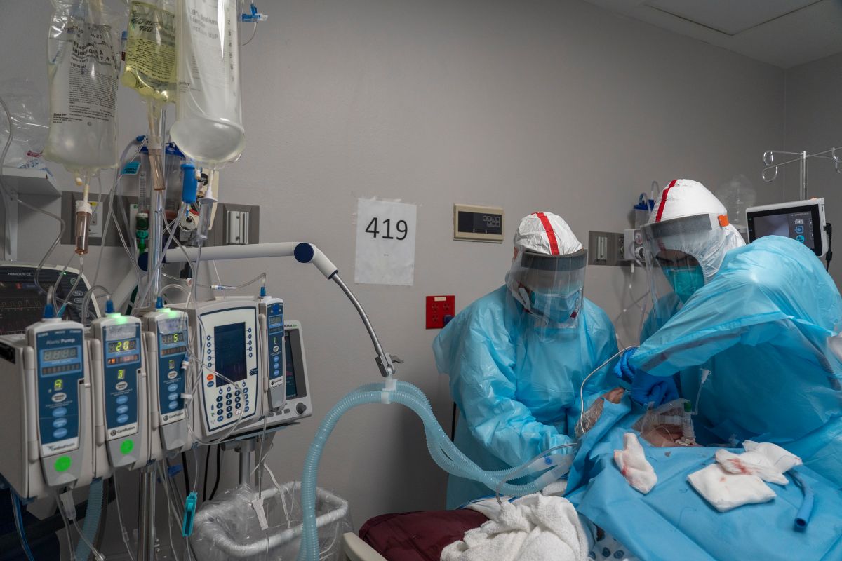 Los miembros del personal médico trabajan para instalar un circuito de ventilador en la garganta de un paciente por COVID-19 en una unidad de cuidados intensivos.
