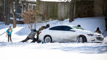 Residentes del este de Austin empujan un automóvil fuera de la nieve el 15 de febrero de 2021 en Austin, Texas.