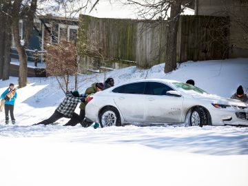Residentes del este de Austin empujan un automóvil fuera de la nieve el 15 de febrero de 2021 en Austin, Texas.