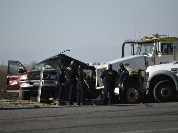 Los investigadores examinan la escena de un accidente entre una camioneta y un camión lleno de grava cerca de Holtville, California, el 2 de marzo de 2021.