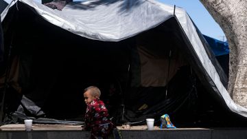 Niño migrante juega cerca de una carpa en un campamento de migrantes en la frontera de México y EE.UU.