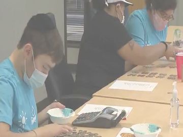 Adultos con discapacidad separan, enrollan y cuentan monedas a través del programa  'Coins for Keshet'. Foto captura Fox 32 Chicago