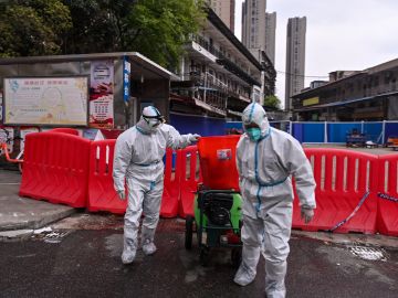 Trabajadores con trajes protectores en el mercado de mariscos de Wuhan, China, ciudad en donde se reportaron los primeros casos registrados de covid-19.