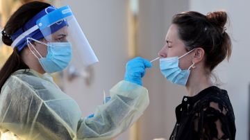 Un trabajador sanitario aplica una prueba de detección de covid-19 a una paciente.