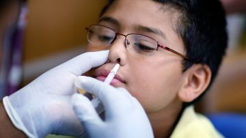 Un niño recibe la vacuna nasal FluMist contra la influenza/gripe.