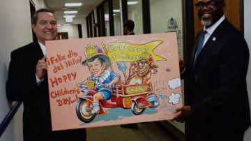 El muralista Óscar Romero muestra un cartel sobre el cómico mexicano Chabelo al alcalde de Chicago, Brandon Johnson. (Cortesía Óscar Romero)