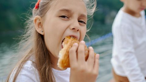 happy little girl eating tasty croissant