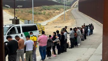 Solicitantes de asilo hacen fila para ser procesados tras cruzar la frontera e ingresar a EEUU.