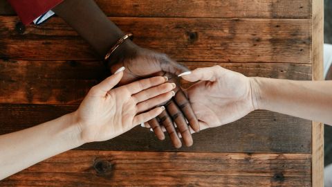 diverse women stacking hands on wooden table