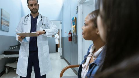 man in white medical scrub suit standing beside girl in blue denim jacket